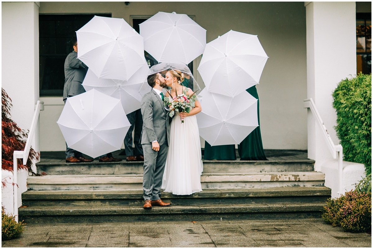 bride and groom pose with umbrellas