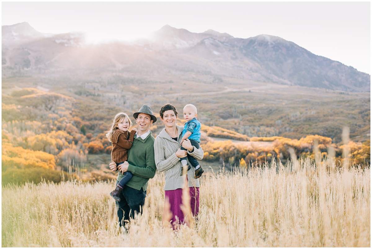 family posing in front of sun set and mountain