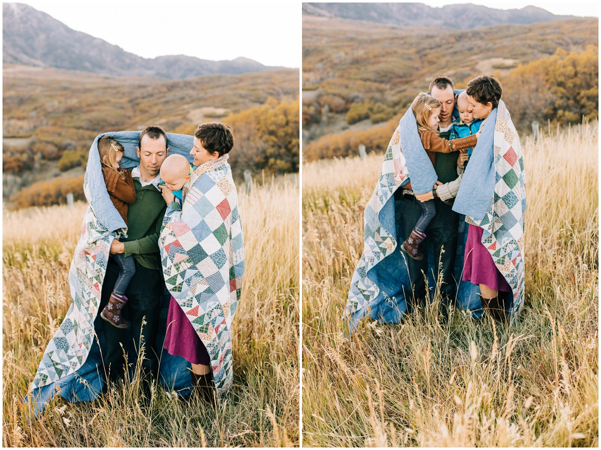 family wrapped in a quilt in a field 