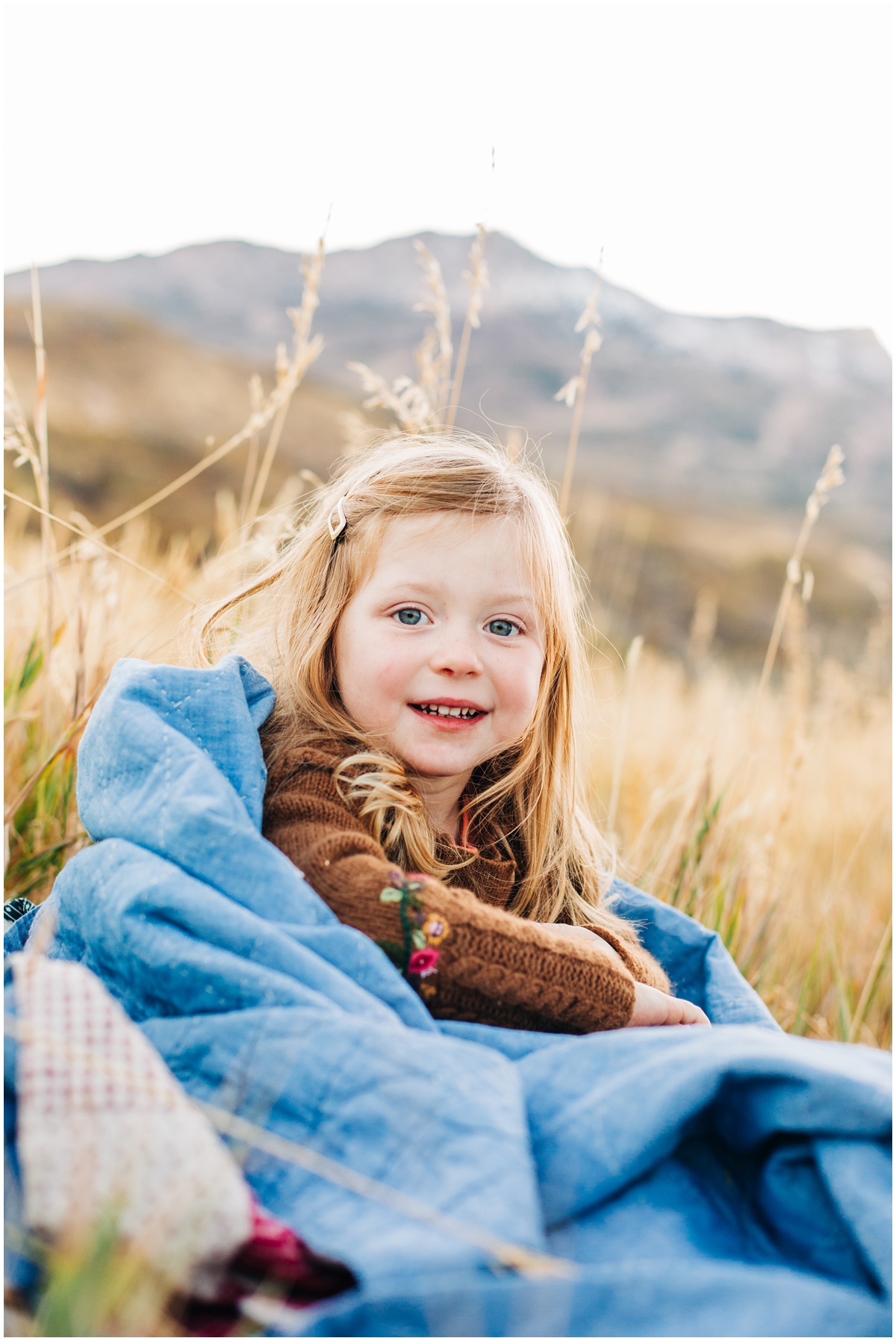 girl wrapped in quilt sitting on grass