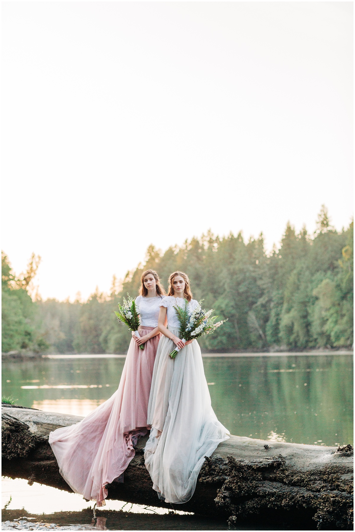 two brides posing on large beach log over water