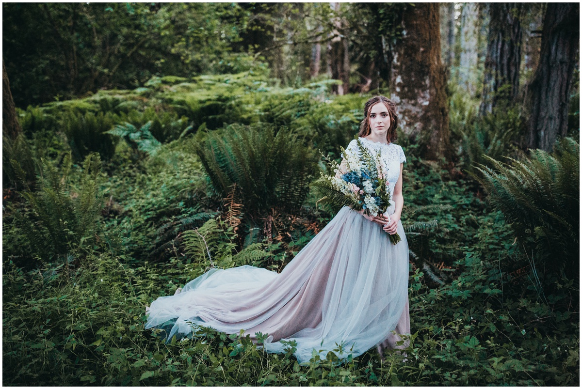 bride poses in rain forest with bouquet