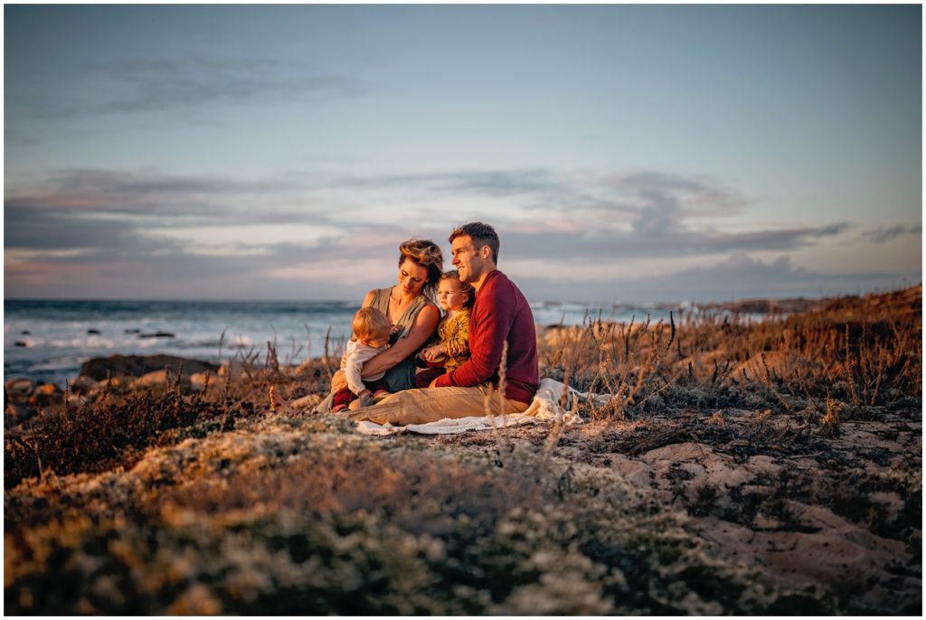 family sitting at asilomar beach sunset