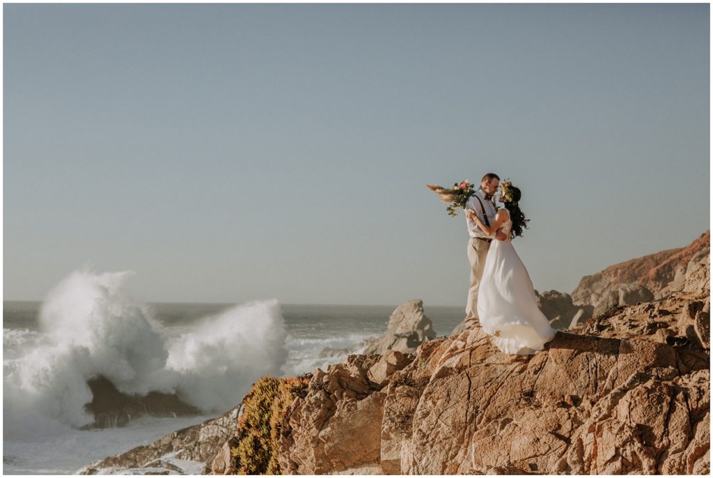 waves crashing on rock by couple at Big Sur California