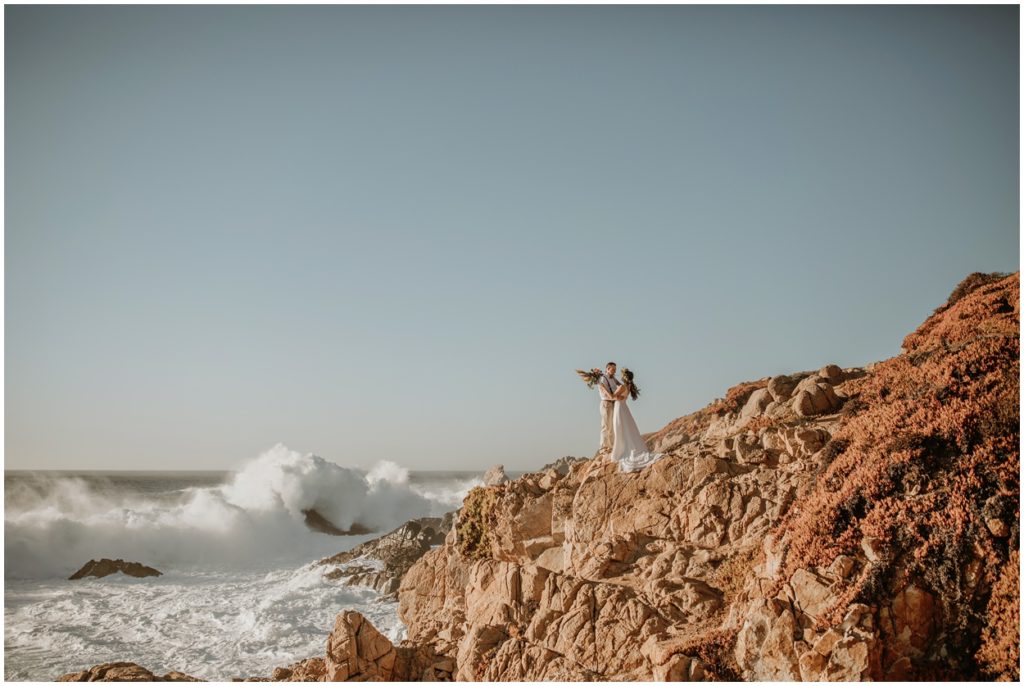 bride and groom stand with view of Pacific Ocean