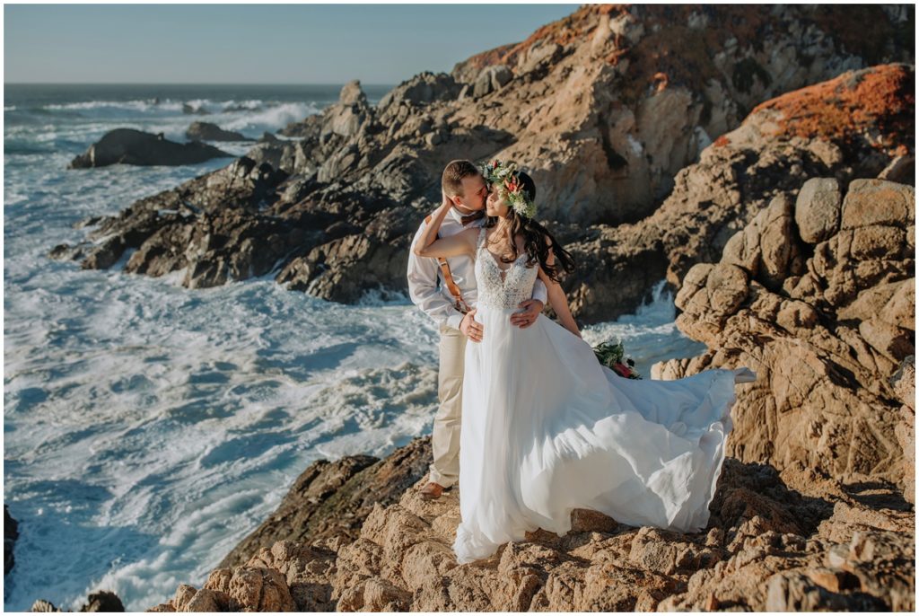 Bride and groom stand on Big Sur cliffs by the ocean