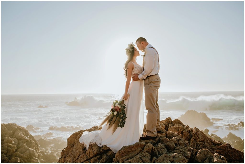backlit bride and groom together by pacific ocean