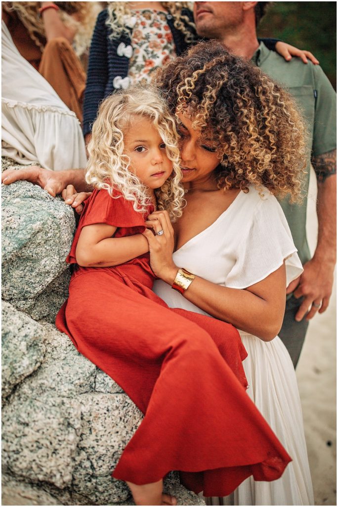 mom comforting curly hair girl at the beach