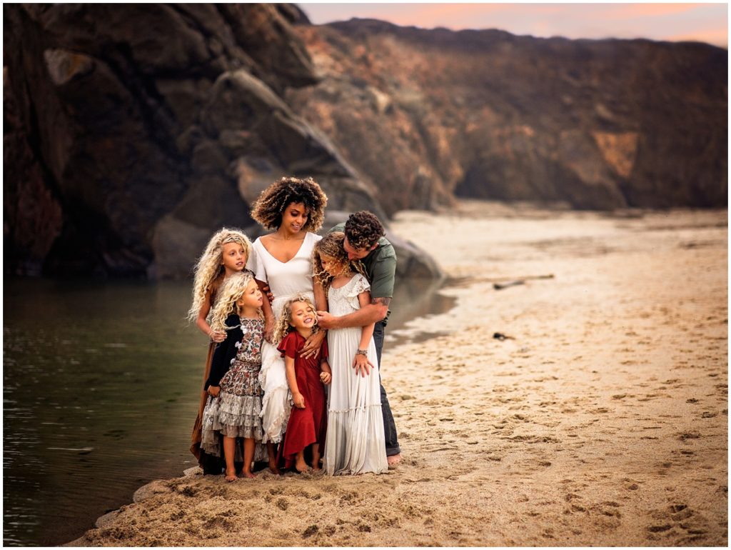 family stands near stream on the beach